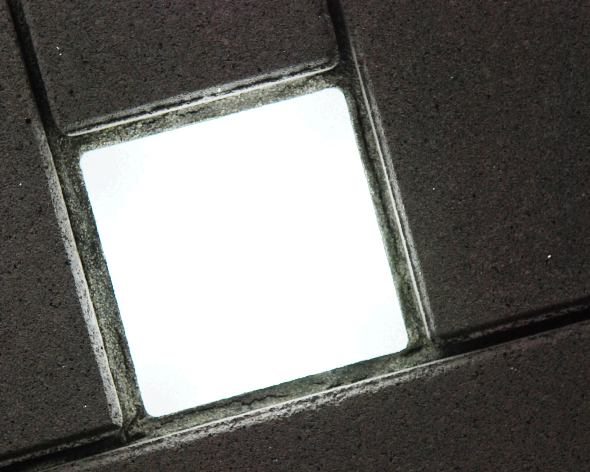 Eingeschalteter Lightstone LED-Pflasterstein im dunklen Betonpflaster, Nahaufnahme