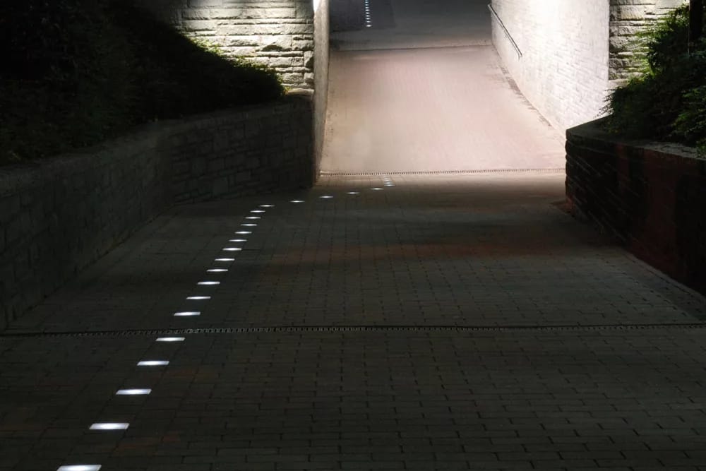Footpath to an underpass at night, illuminated stones run along its edge