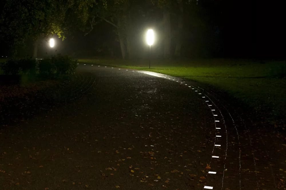 Curved path through a park at night, illuminated stones follow the edge of the path