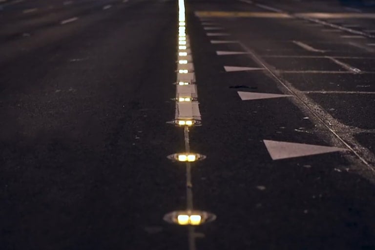 Multi-lane road at night, a row of lit Road Studs marks the dividing line