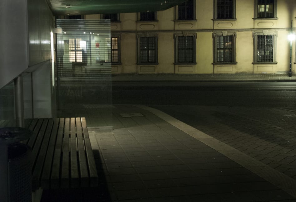 Haltestelle bei Nacht, beleuchtet nur durch eine Fahrplanvitrine