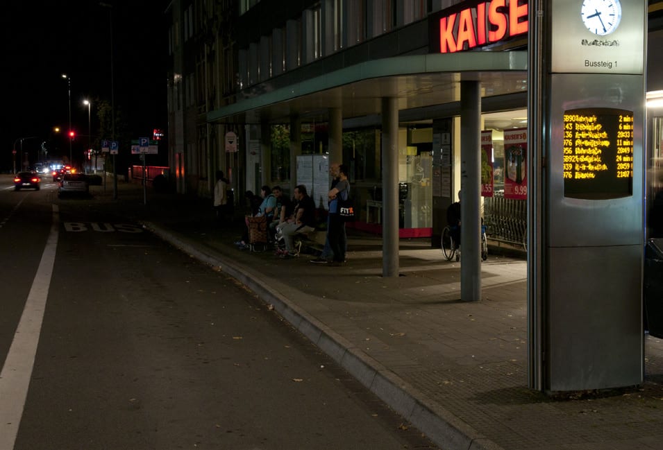 Haltestelle bei Nacht, der Leitstreifen hebt sich farblich kaum vom Pflaster ab