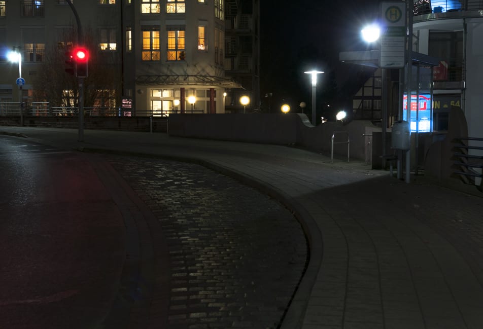 Haltestelle bei Nacht mit einer niedrigen, blendenden Mastleuchte