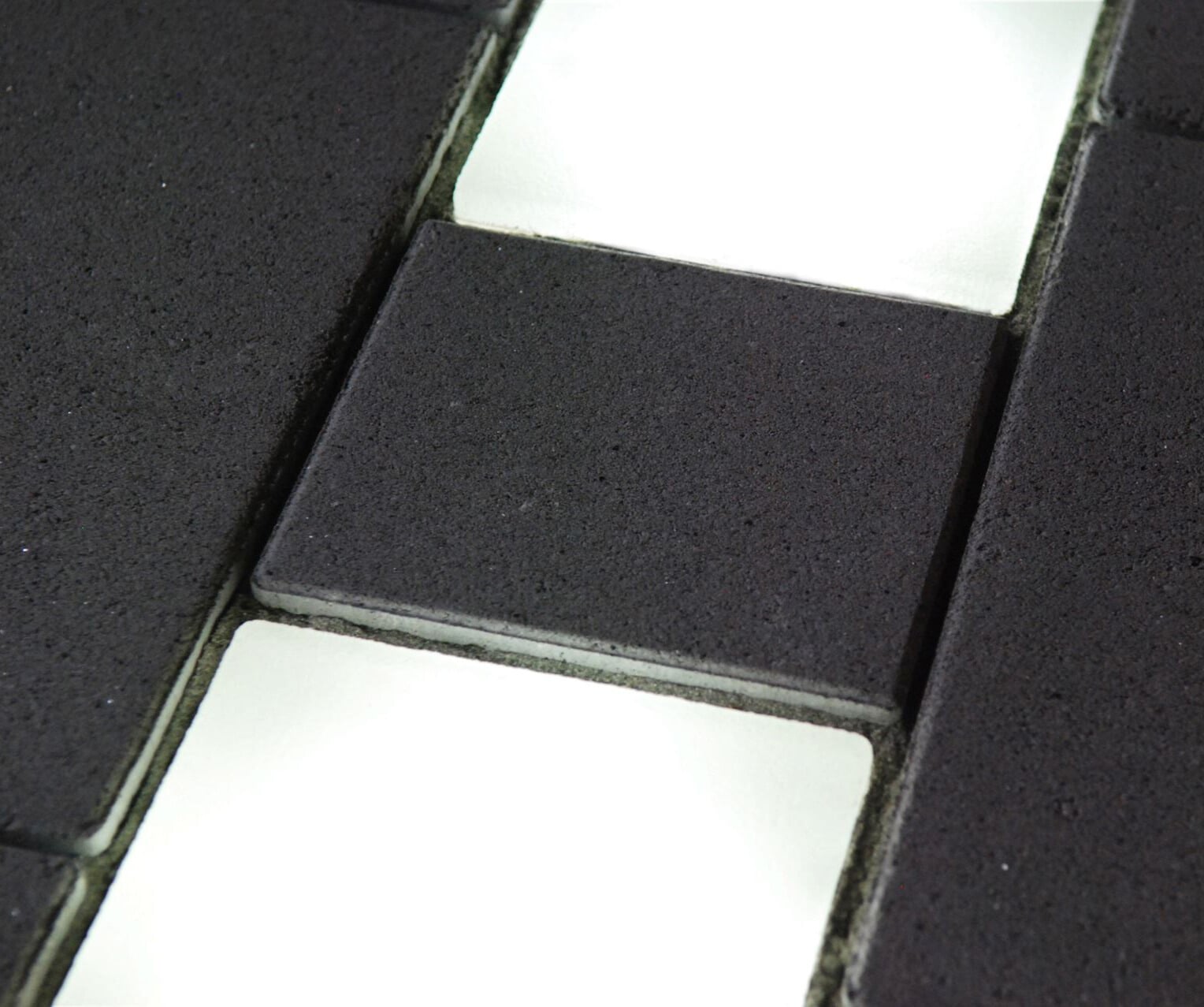 STYLE bei Nacht: zwei leuchtende Lightstone LED-Pflastersteine mit glatter Oberfläche zwischen dunklen Betonsteinen