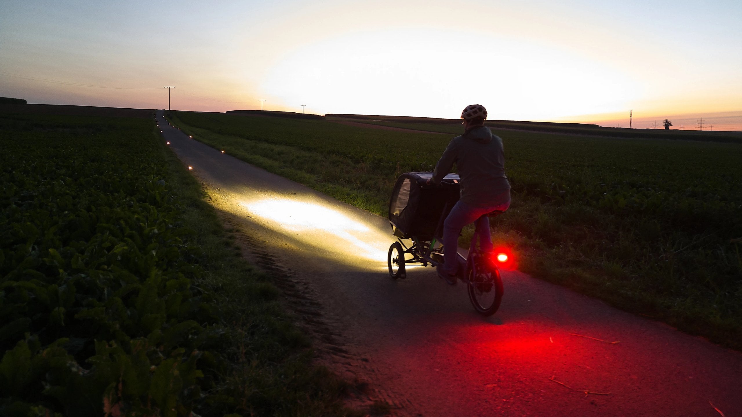 Cyclist with a trailer and their own light on a cycle path at dusk