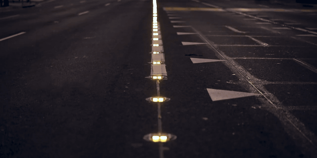Mehrspurige Straße bei Nacht, eine Reihe leuchtender Road Studs markiert die Trennlinie