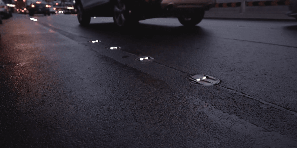 Nasse Stadtstraße in der Dämmerung, Road Studs trennen den Radweg von der Fahrbahn